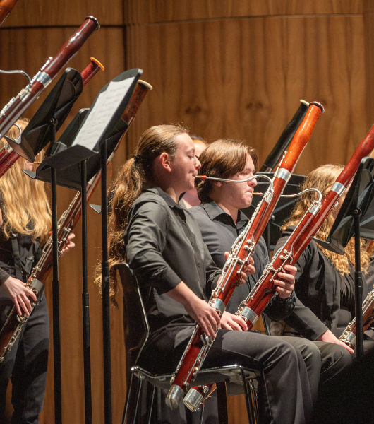 Bassoon players dressed in black playing in a concert hall.